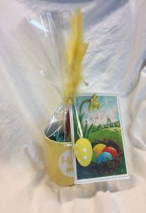 Bilde av en påskehilsn med kort, fjær, egg og kopp med godteri.